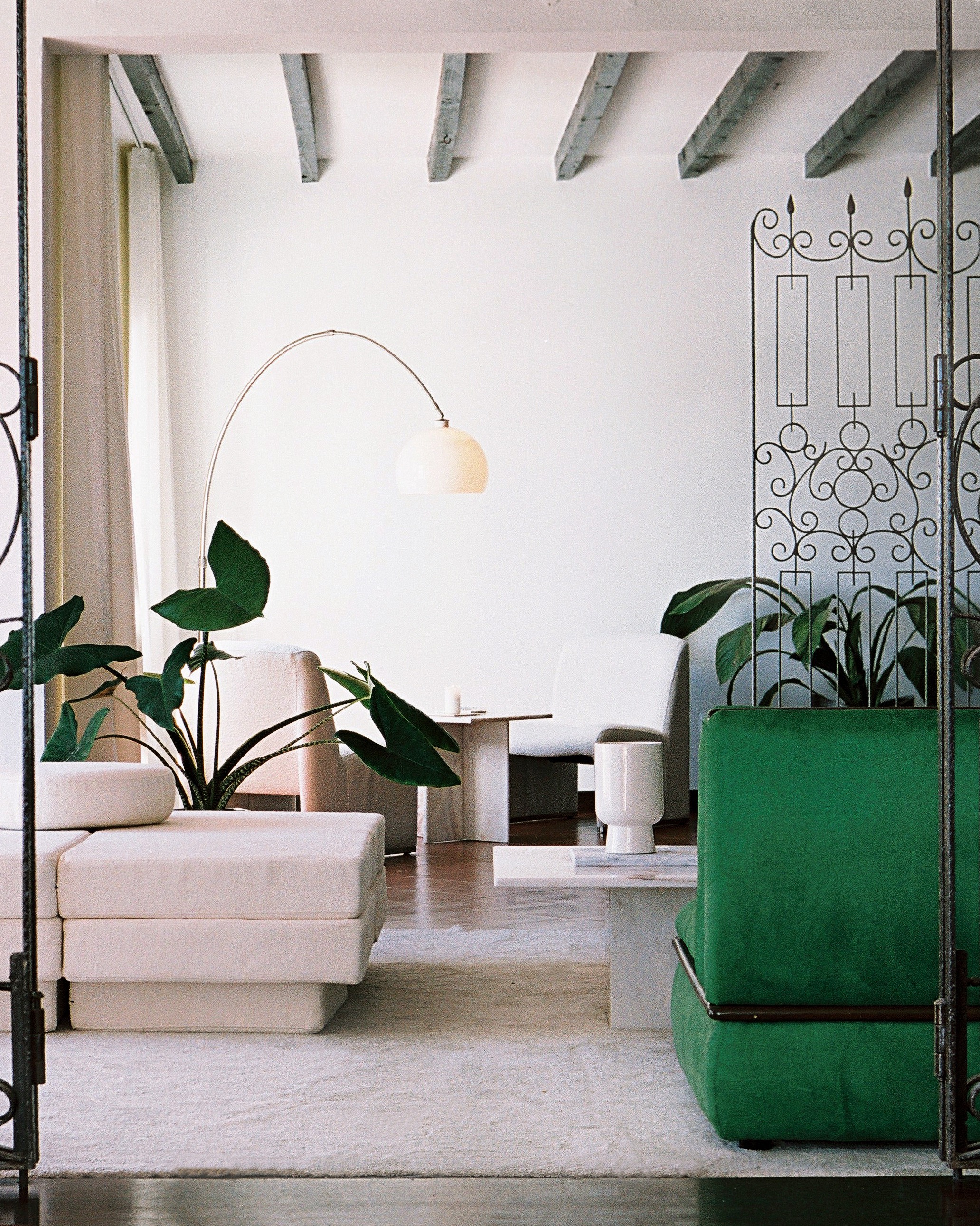 Boutique hotel lobby with arc lamp, wrought-iron gates, and tropical plants